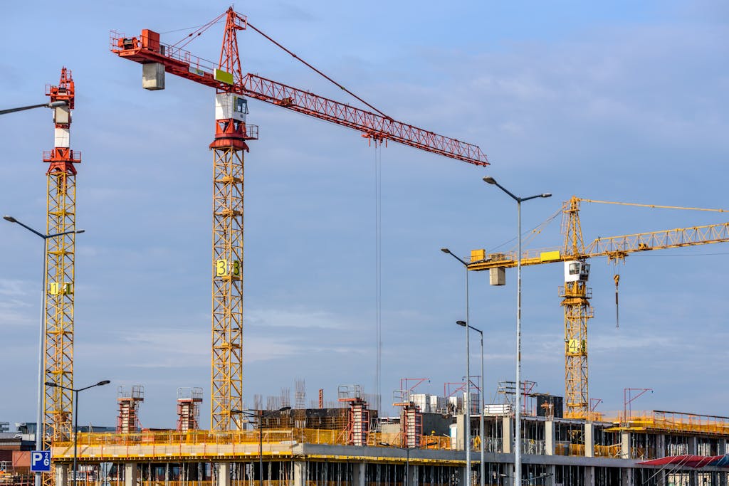 Three Yellow and Red Tower Cranes Under Clear Blue Sky